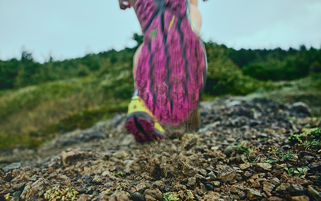 Active close up shot of the bottom of the Brooks Cascadia 19 while running on a rocky trail